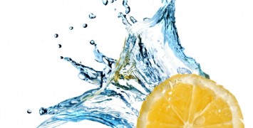 Fresh lemon dropped into water with splash isolated on white